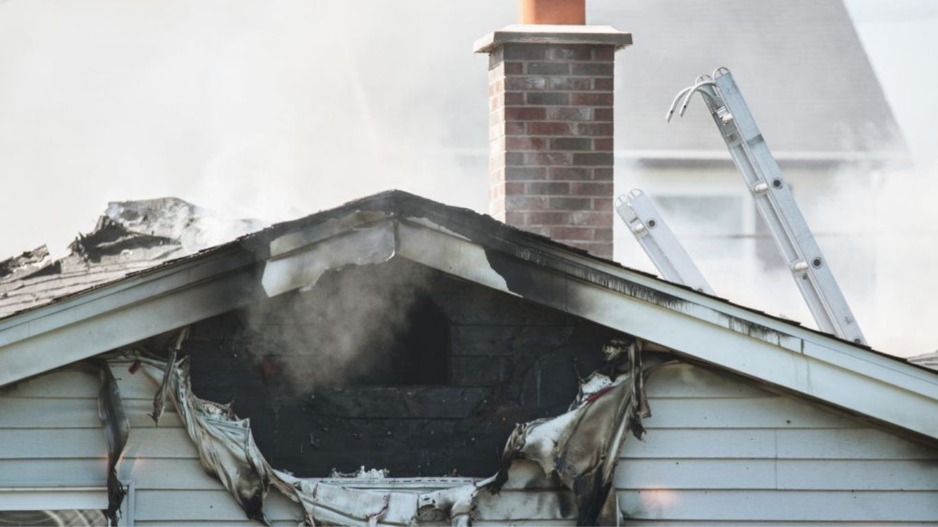 Bring Fresh Air Back Home with Professional Smoke Removal Services Fire-damaged house roof with visible soot and damage, highlighting professional smoke removal services.